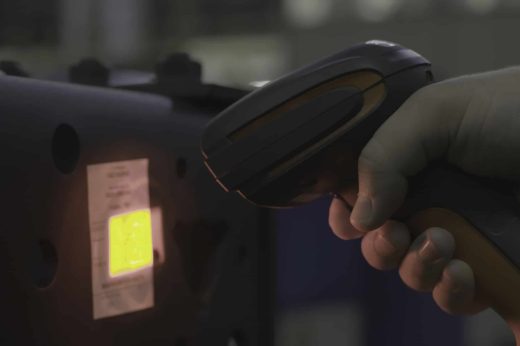 A man scanning a barcode, buying and selling concept. Close up of hand holding bar code scanner, scanning packages labels with laser on box.